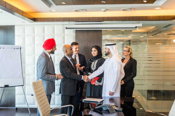 Business professionals in formal attire shaking hands in a modern office, aligning with advantages of RAKEZ Free Zone.